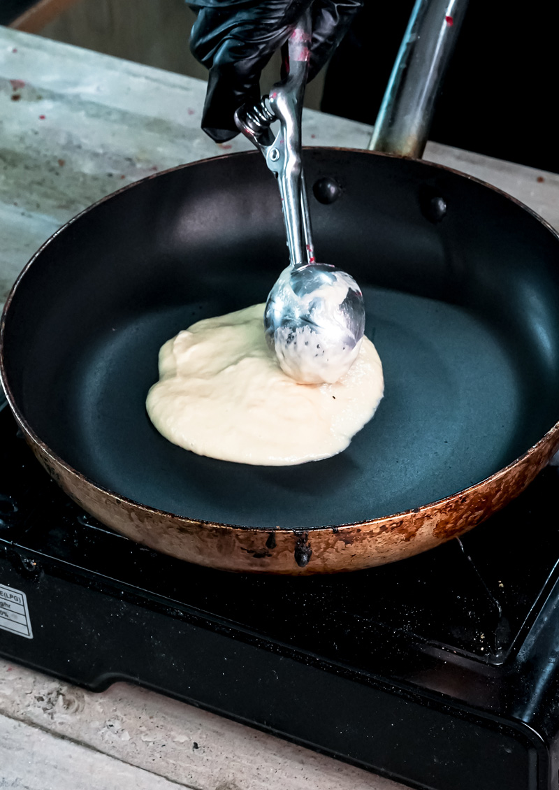 Scooping gluten-free pancake batter into non-stick pan