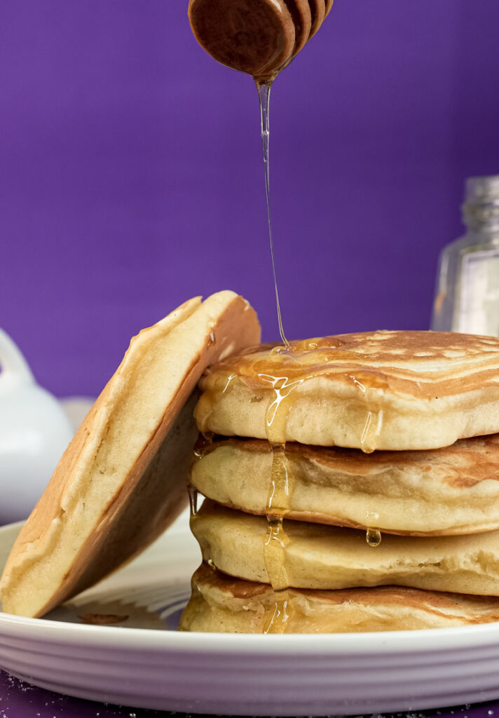 Honey being drizzled over gluten-free pancakes