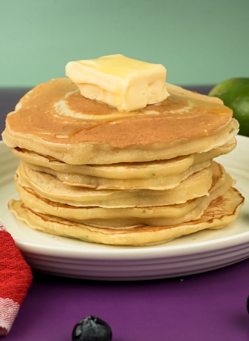 Tall stack of lemon ricotta pancakes with butter pat on top