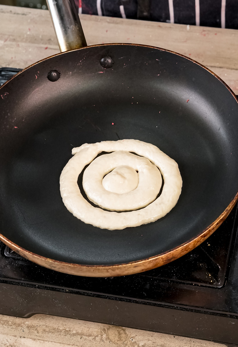 Pouring pancake batter in spiral pattern in non-stick pan