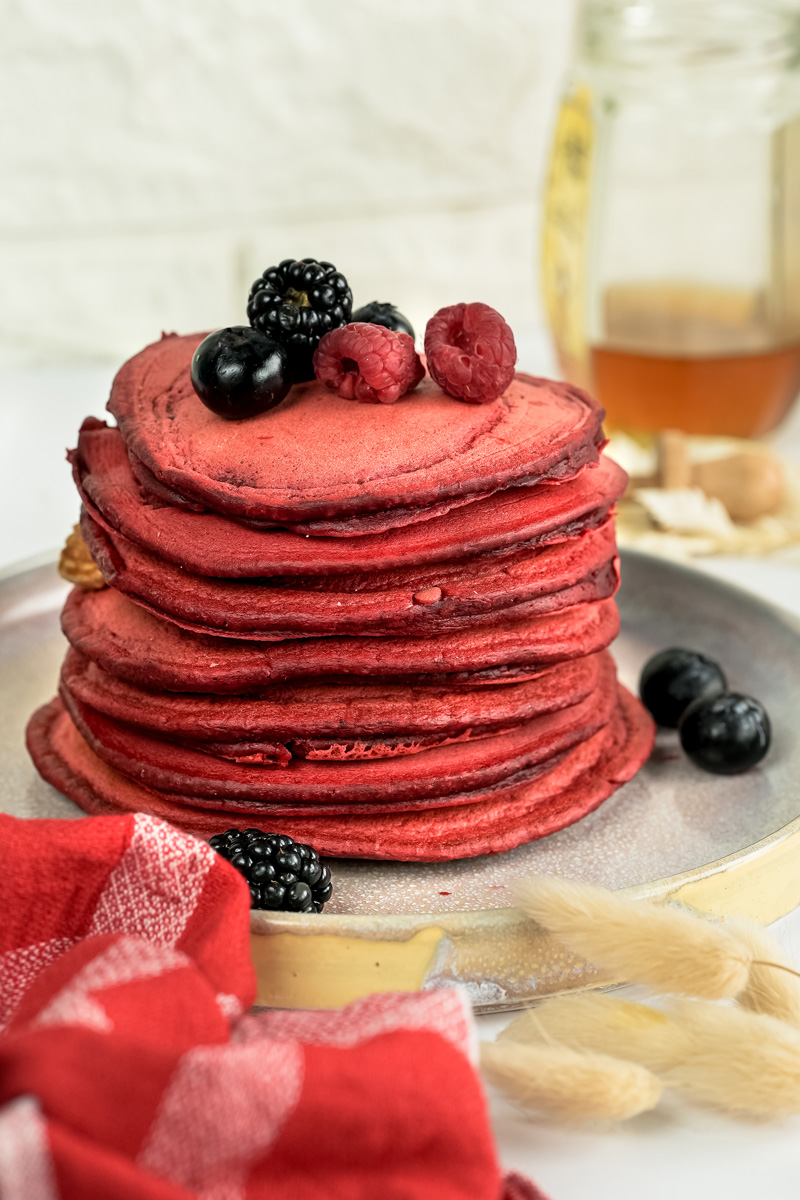 Tall red velvet pancake stack with blueberries and raspberries