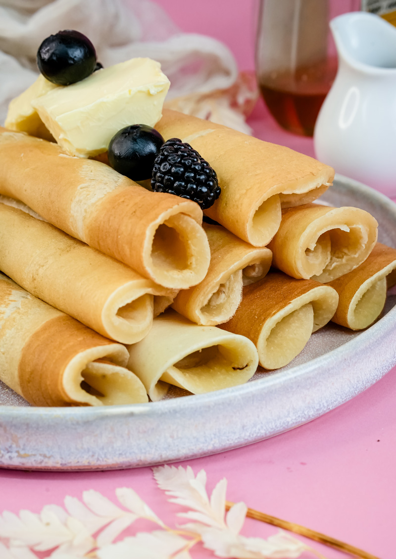 Close-up of rolled pancakes showing hollow tubes with berries